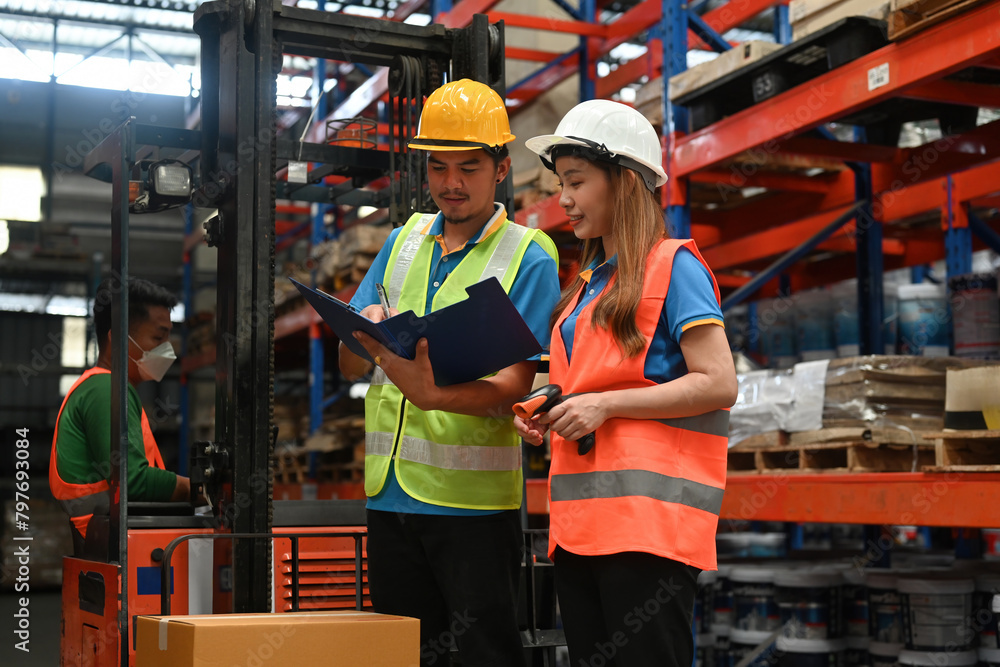 Two Warehouse workers examining the result on a document in logistics distribution warehouse Two Warehouse workers examining the result on a document in logistics distribution warehouse
