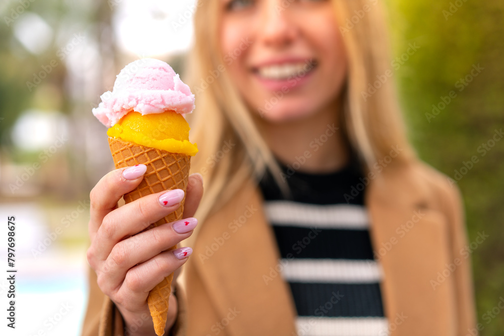 Young pretty blonde woman with a cornet ice cream at outdoors