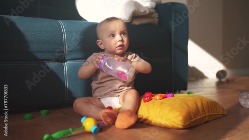 baby plays on the floor with toys. happy family kid dream concept. baby shakes a plastic bottle plays with a toy development of fine motor skills. baby toddler lifestyle playing on the floor in