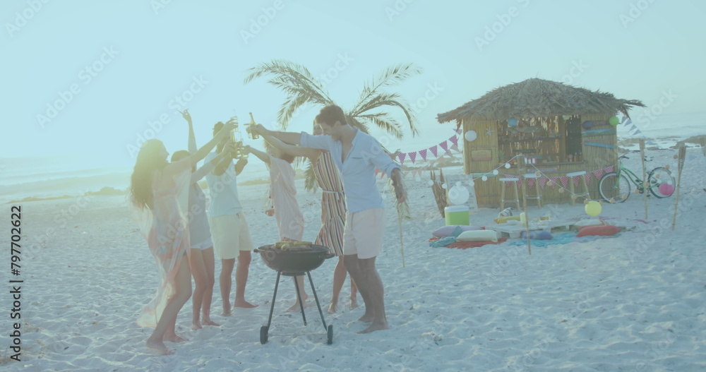 Naklejka premium Group of friends enjoying a beach barbecue at sunset