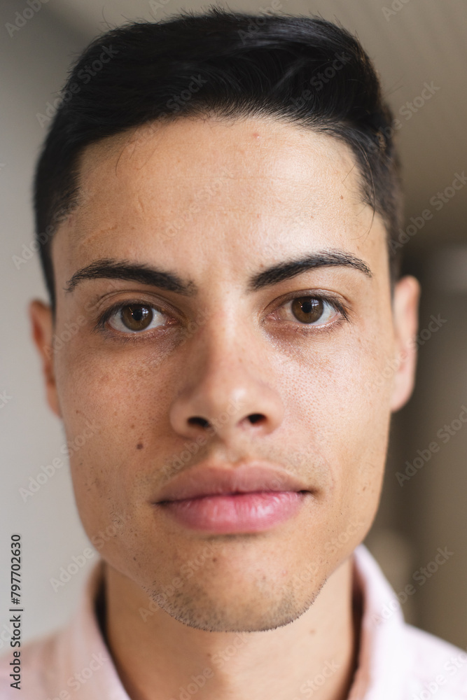 Biracial man with short dark hair looks at camera in modern office Biracial man with short dark hair looks at camera in modern office