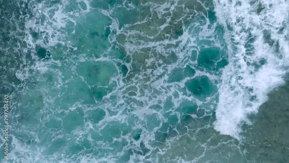 Top Down Slow Motion Drone View of turquoise clear water and crashing waves over shallow coral reef in Uluwatu Bali Indonesia. Clear water and abstract wave action. Top Down Slow Motion Drone View of turquoise clear water and crashing waves over shallow coral reef in Uluwatu Bali Indonesia. Clear water and abstract wave action.