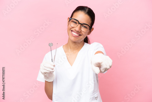 Dentist Colombian woman isolated on pink background pointing front with happy expression