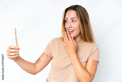 Young caucasian woman brushing teeth isolated on white background with surprise and shocked facial expression