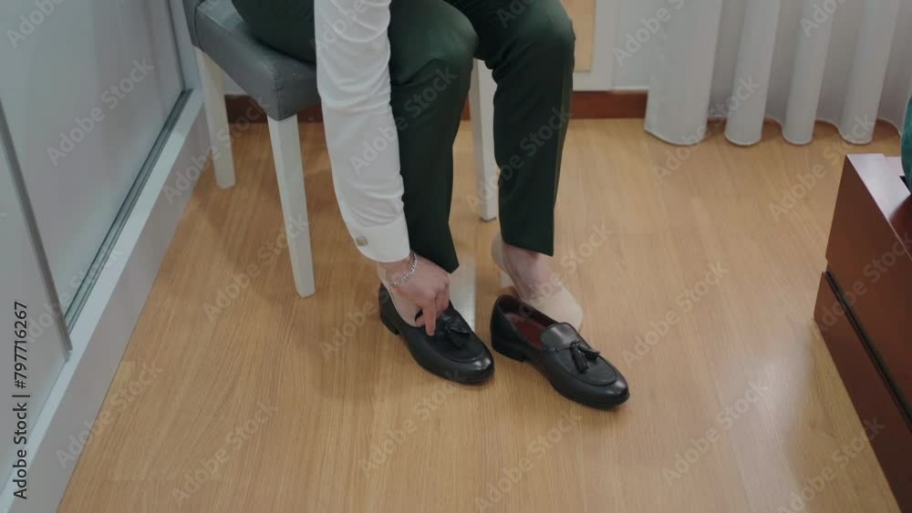 Close-up of person sitting and tying elegant black dress shoes indoors Close-up of person sitting and tying elegant black dress shoes indoors