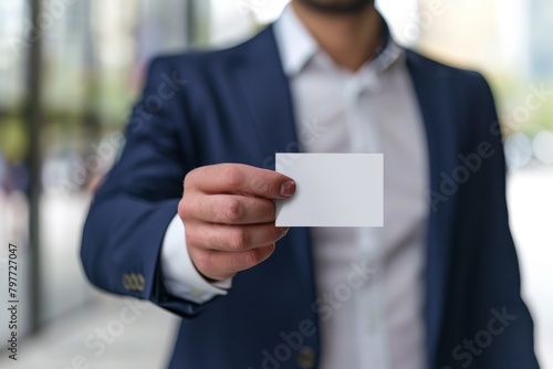 Close-up of a male executive's hand offering a blank business card.