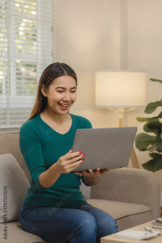 A beautiful Asian woman is using a communication device to talk to long-distance friends abroad, Relax on the couch at home and do your own recreational activities. A beautiful Asian woman is using a communication device to talk to long-distance friends abroad, Relax on the couch at home and do your own recreational activities.
