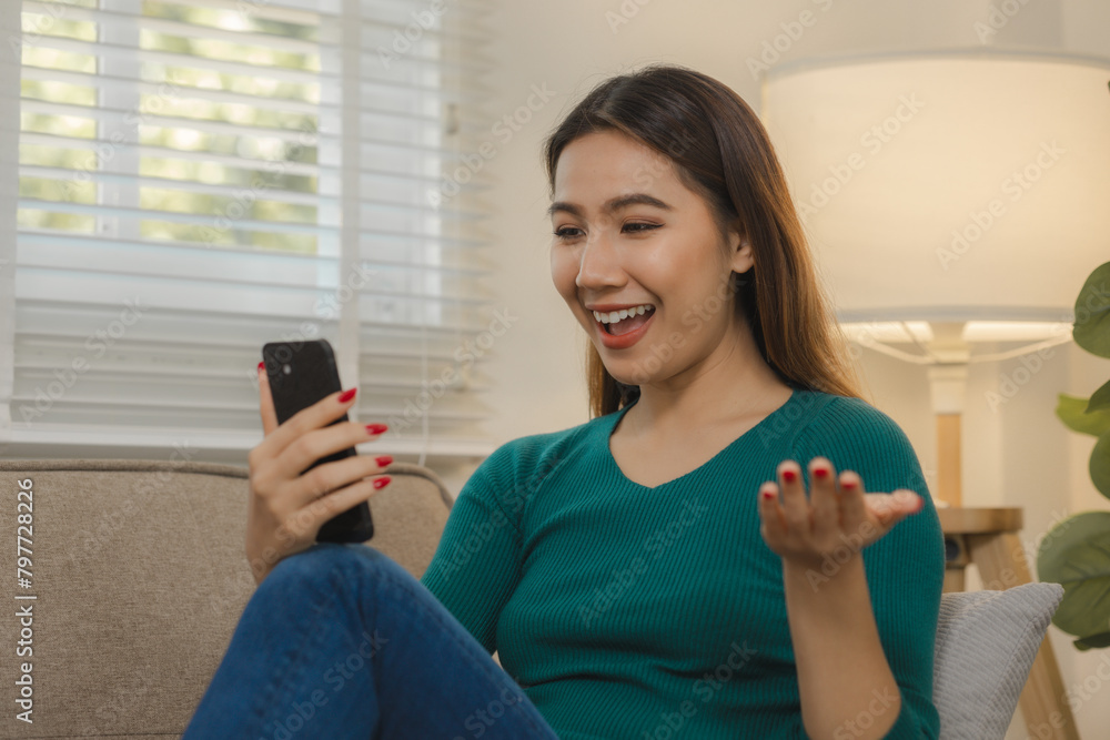 A beautiful Asian woman is using a communication device to talk to long-distance friends abroad, Relax on the couch at home and do your own recreational activities. A beautiful Asian woman is using a communication device to talk to long-distance friends abroad, Relax on the couch at home and do your own recreational activities.