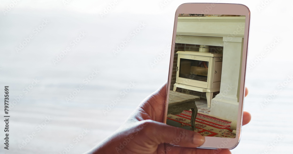 Obraz premium Image of person using smartphone with house sitting room fireplace interiors displayed on screen