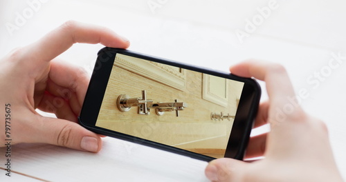 Image of person using smartphone with house bathroom interiors displayed on screen