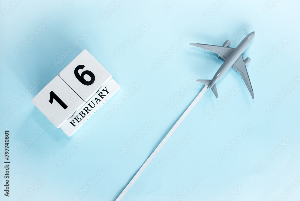 February calendar with number 16. Top view of calendar with flying passenger plane. Scheduler. Travel concept. Copy space. February calendar with number 16. Top view of calendar with flying passenger plane. Scheduler. Travel concept. Copy space.