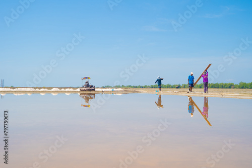 Farmers making heaps of raw sea salt piles with sea. Farm field outdoor. Nature material in traditional salt industry in Thailand. Asia culture. Agriculture lifestyle people.