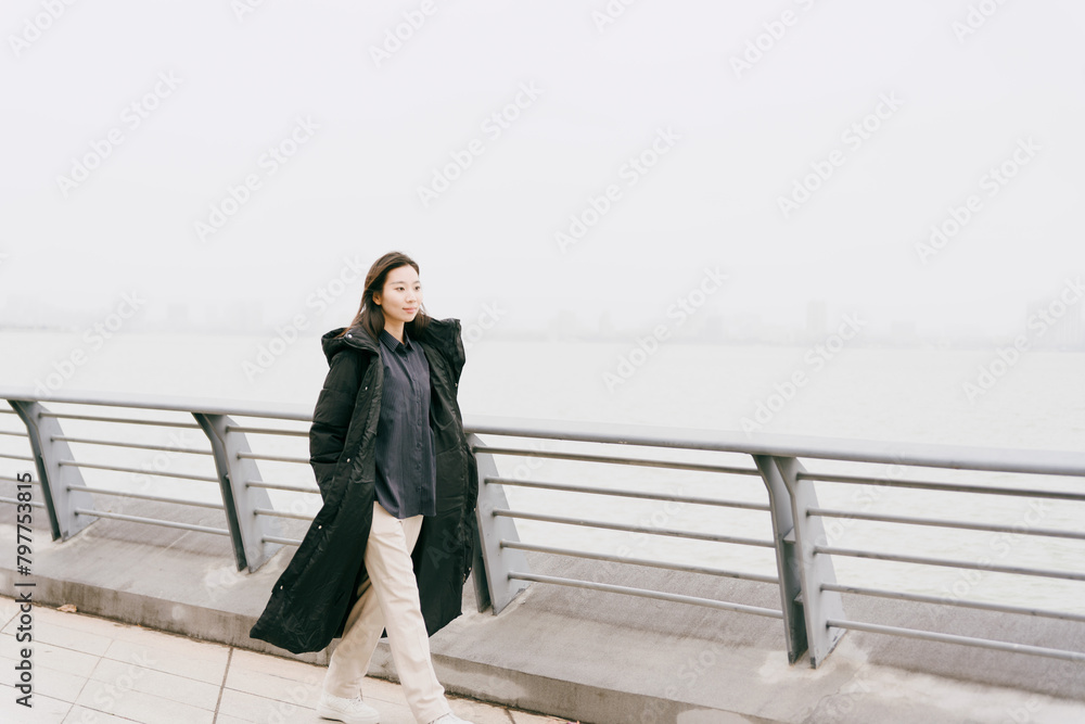 On cloudy winter days, Asian women walk along the seaside boardwalk On cloudy winter days, Asian women walk along the seaside boardwalk