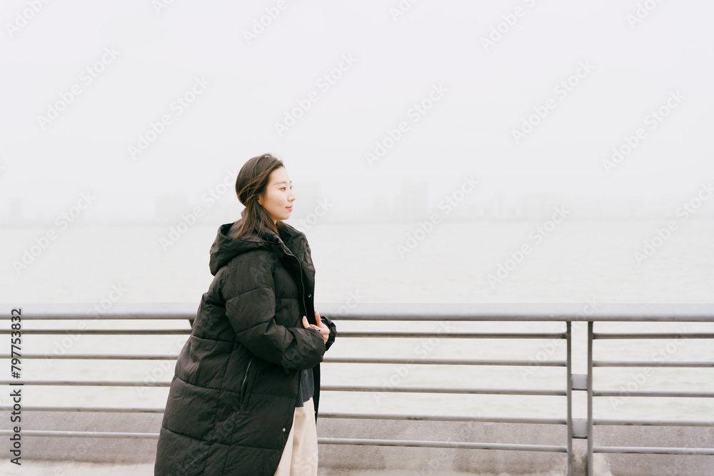 On cloudy winter days, Asian women walk along the seaside boardwalk On cloudy winter days, Asian women walk along the seaside boardwalk