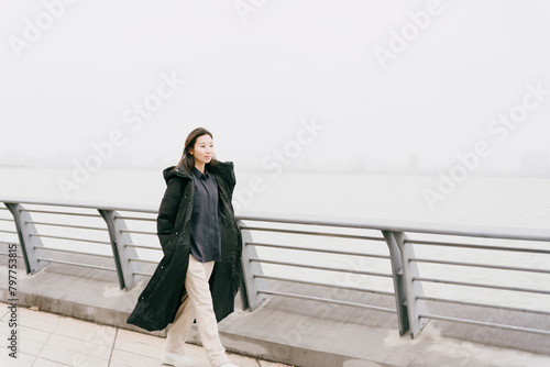 On cloudy winter days, Asian women walk along the seaside boardwalk