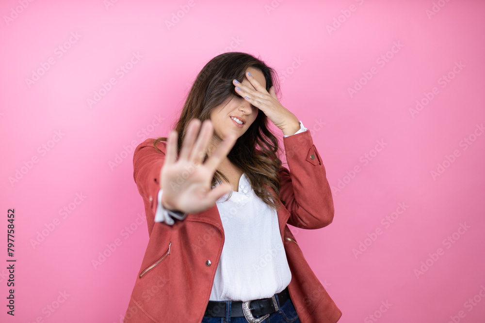 Young beautiful woman wearing casual jacket over isolated pink background with hands and doing stop gesture with sad and fear expression.Embarrassed and negative concept Young beautiful woman wearing casual jacket over isolated pink background with hands and doing stop gesture with sad and fear expression.Embarrassed and negative concept