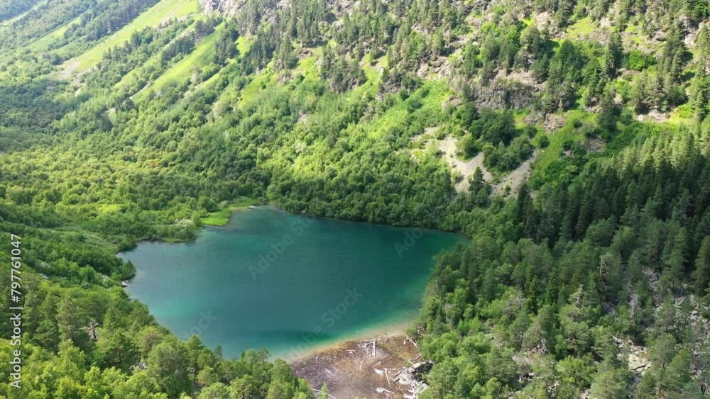 A smooth flight through the forest between the mountains over a mountain lake with turquoise water on a sunny day. Caucasus. A smooth flight through the forest between the mountains over a mountain lake with turquoise water on a sunny day. Caucasus.