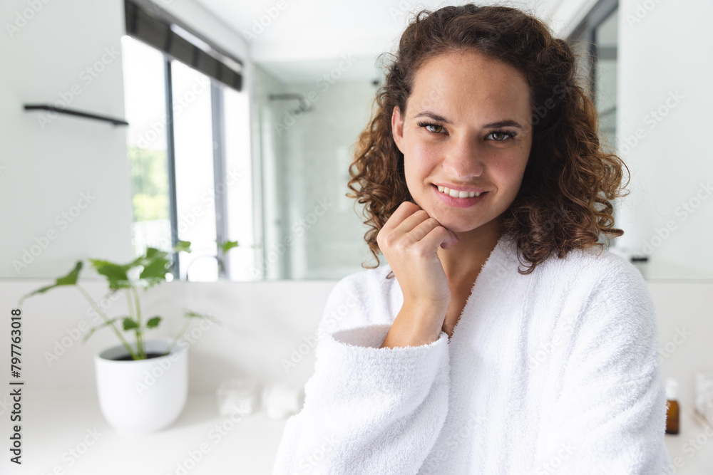 A young Caucasian woman in white robe, standing in a bathroom at home, copy space A young Caucasian woman in white robe, standing in a bathroom at home, copy space