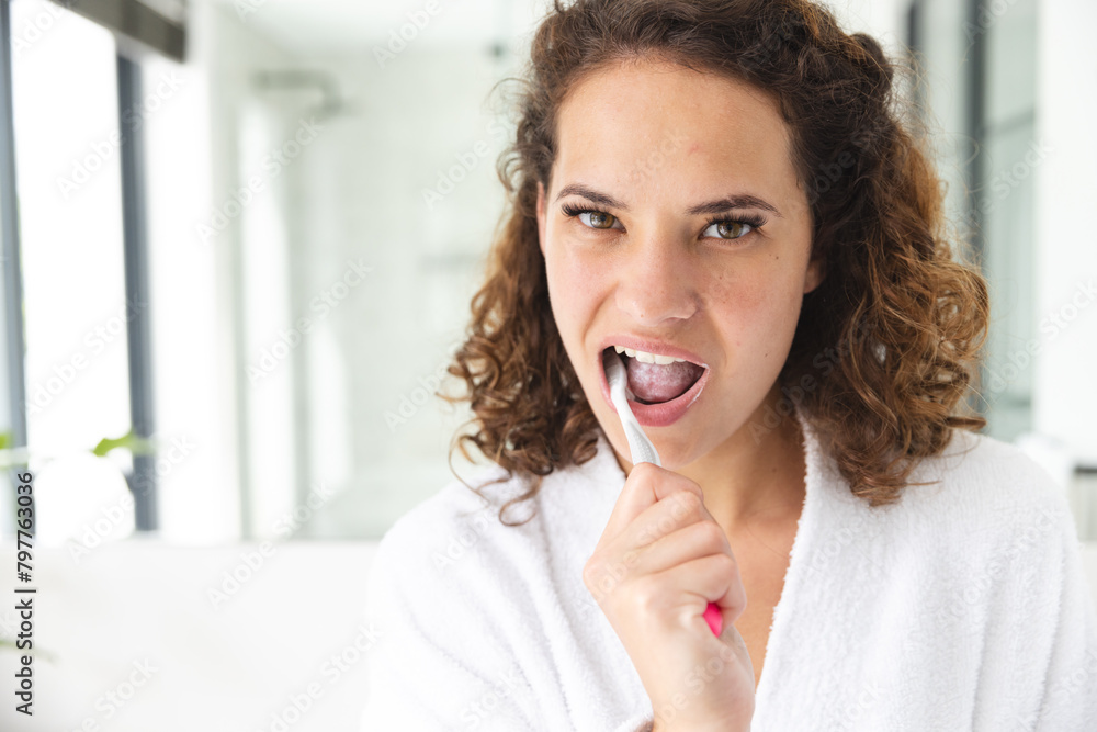 A young Caucasian woman brushing teeth at home in bathroom, copy space A young Caucasian woman brushing teeth at home in bathroom, copy space