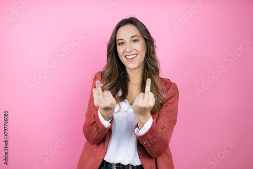 Young beautiful woman wearing casual jacket over isolated pink background showing middle finger doing fuck you bad expression, provocation and rude attitude. screaming excited photo