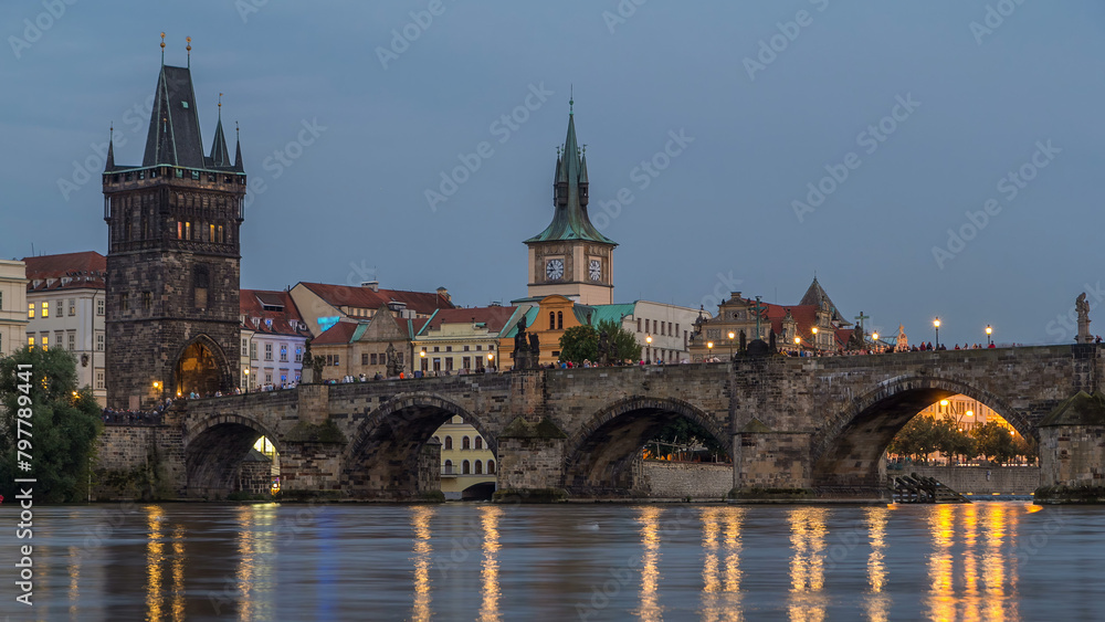 Fototapeta premium The Charles Bridge day to night timelapse over the Vltava River reflected in water in Prague, Czech Republic