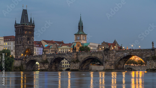 The Charles Bridge day to night timelapse over the Vltava River reflected in water in Prague, Czech Republic