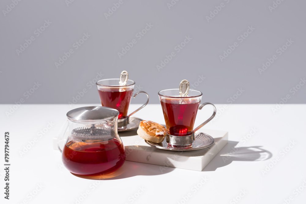 Dos tazas de té rojo con pasteles y dulces sobre mármol y fondo gris	