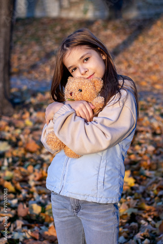 Girl hugging teddy bear in autumn park