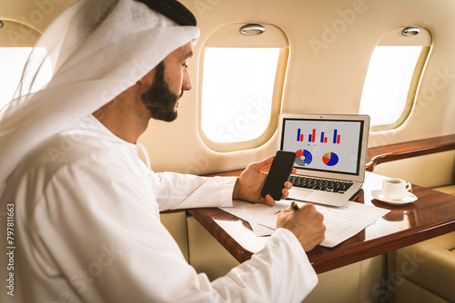 Arabian businessman wearing corporate business emirate kandora flying on luxury private jet, concepts about travel, transportation and wealthy lifestyle photo