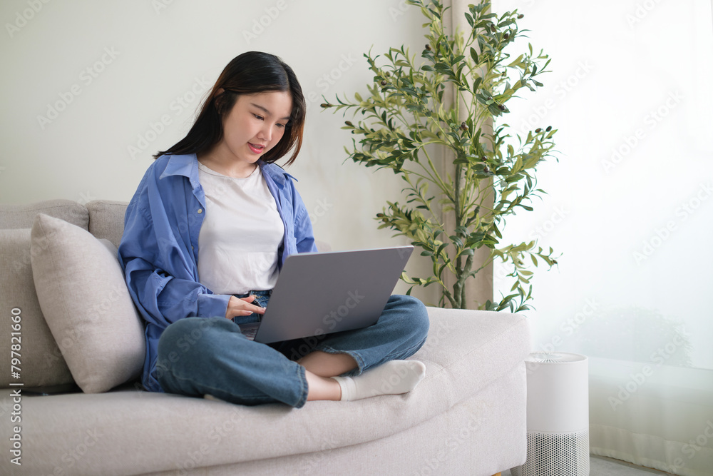 Smiling young woman freelancer sitting on couch and using laptop, remote work or studying online. Smiling young woman freelancer sitting on couch and using laptop, remote work or studying online.