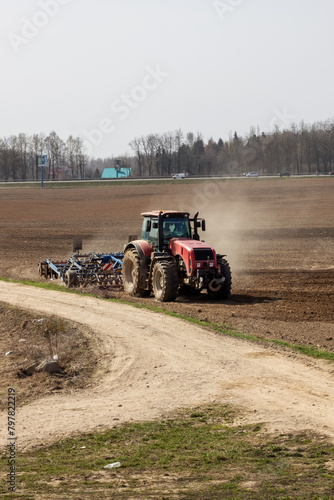 Red tractor is plowing a field closeup