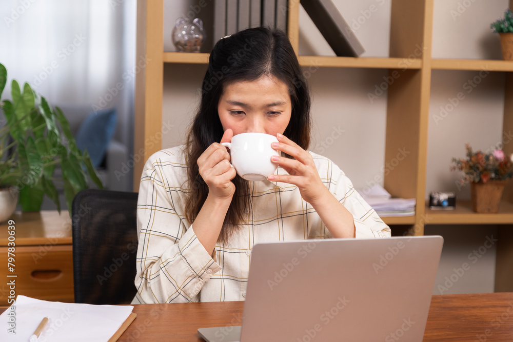Young female in casual clothes sitting and drinking coffee working at home office woman working on the computer, small business architect entrepreneur concentrated business planning, female freelancer Young female in casual clothes sitting and drinking coffee working at home office woman working on the computer, small business architect entrepreneur concentrated business planning, female freelancer