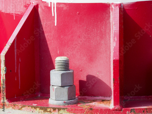 Closeup of nuts and bolts connecting a red pylon to its base.