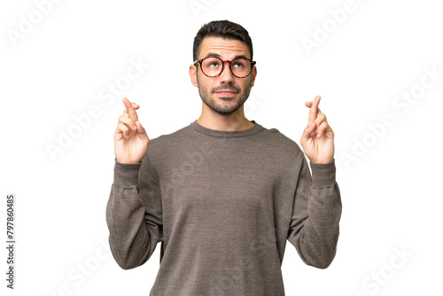 Young handsome caucasian man over isolated background with fingers crossing and wishing the best