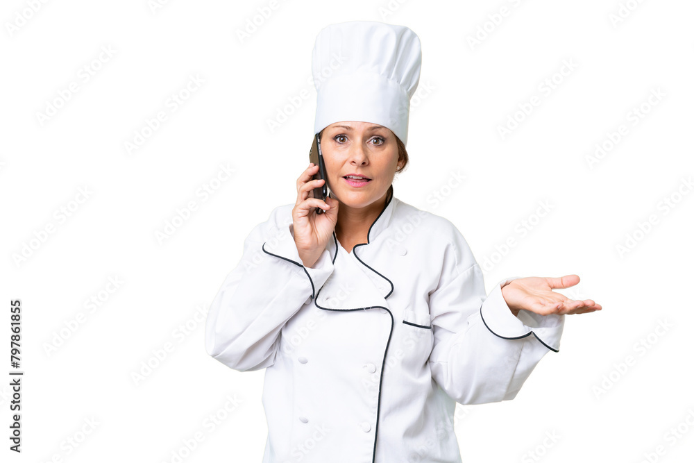 Middle-aged chef woman over isolated background keeping a conversation with the mobile phone with someone Middle-aged chef woman over isolated background keeping a conversation with the mobile phone with someone