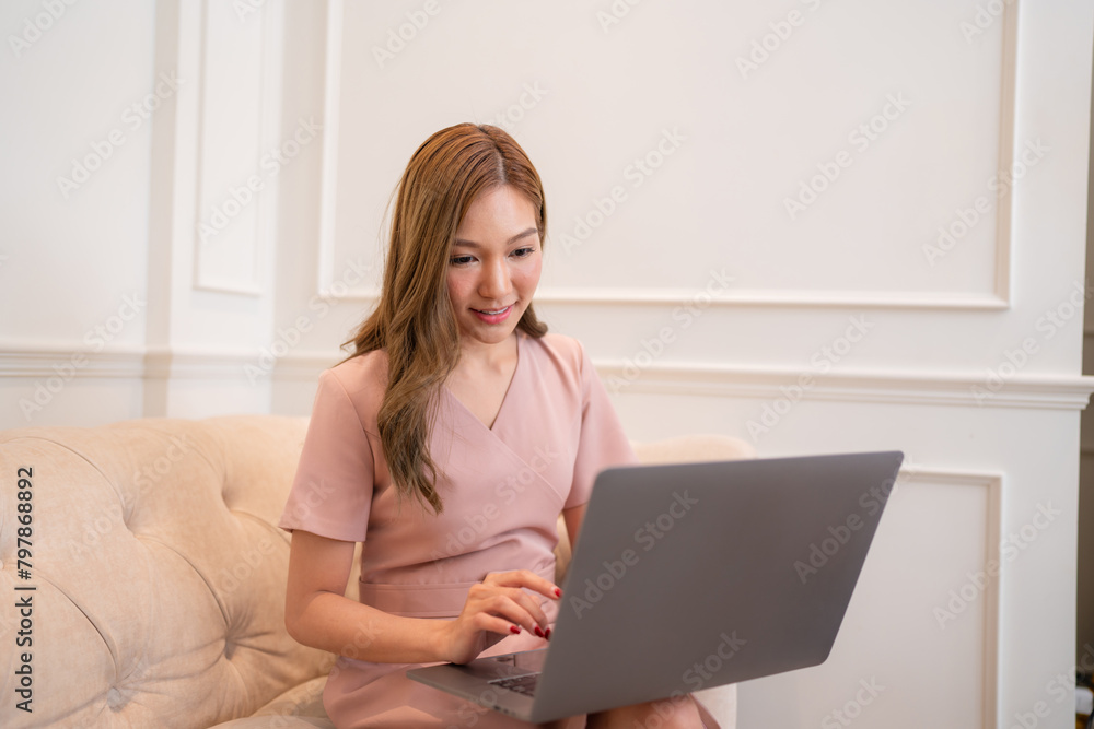 Happy and smiling businesswoman talking on cellphone and typing on laptop, office worker happy with achievement results, at work inside office building. Happy and smiling businesswoman talking on cellphone and typing on laptop, office worker happy with achievement results, at work inside office building.