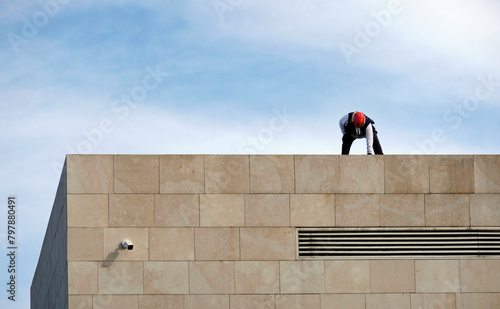 Anonymous worker with a red helmet working on a roof
