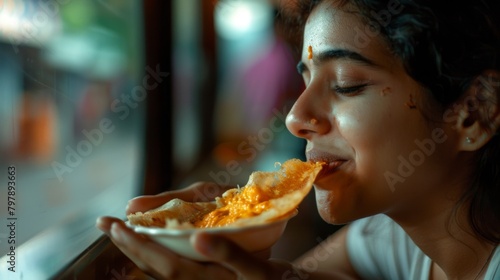 A woman savoring a bite of crispy dosa dipped in tangy coconut chutney  her eyes closed in blissful enjoyment of the flavorful dish.