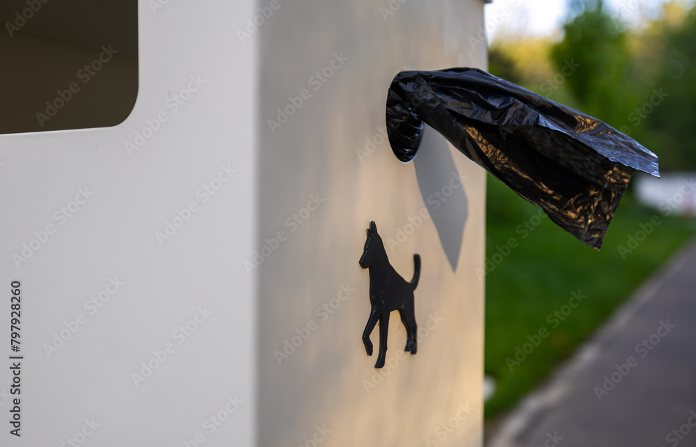 Dog waste bags in a park. Close up photo of a garbage with plastic disposable bags for dog poop while walking them outside.
