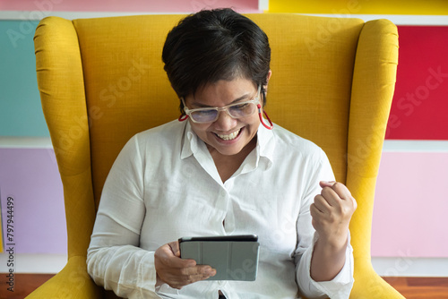 Happy and Joyful Middle aged Asian aunt, aged woman using computer tablet, positive expression