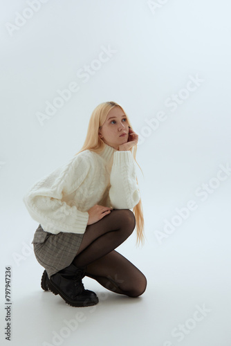 Photos A cute girl in a white sweater poses on a light background in Korean-style photo