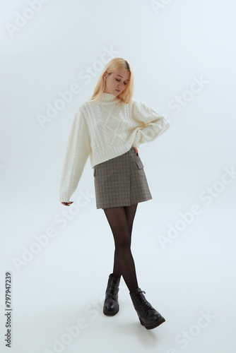 Tableau sur toile A cute girl in a white sweater poses on a light background in Korean-style photo
