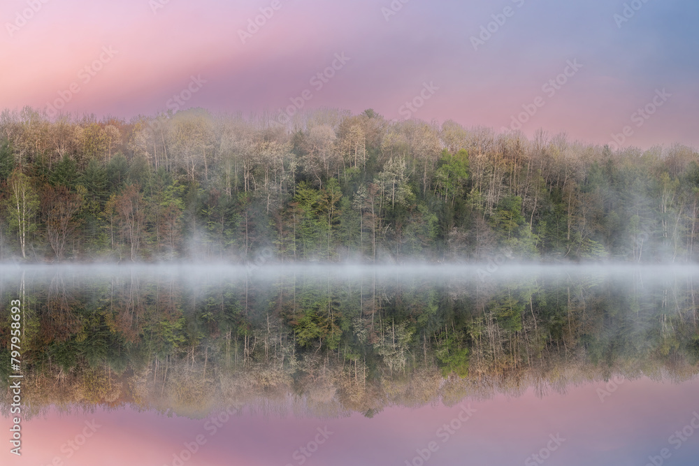 Fototapeta premium Foggy spring landscape at dawn of Moccasin Lake with mirrored reflections in calm water, Hiawatha National Forest, Michigan's Upper Peninsula, USA