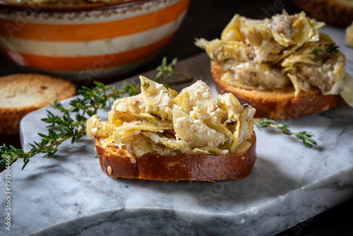 Bruschetta with artichoke salad, Parmesan cheese, truffle salsa and thyme leaves.