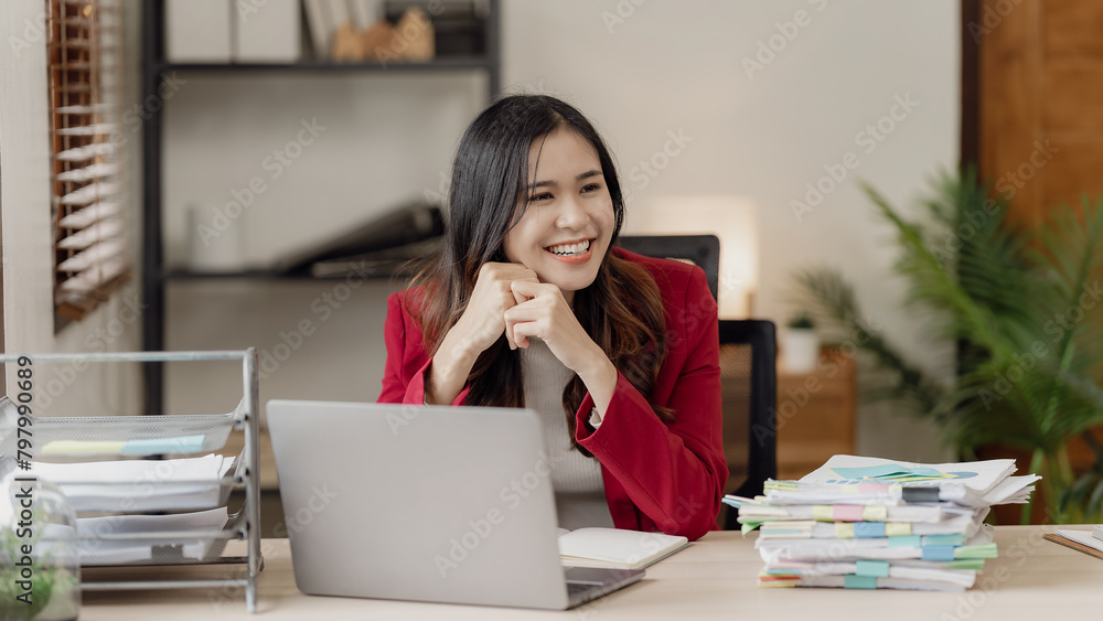 Asian woman using laptop computer and working at office with calculator document on table, planning to analyze financial report, business plan, financial investment Asian woman using laptop computer and working at office with calculator document on table, planning to analyze financial report, business plan, financial investment