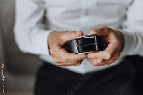 A man is holding a belt in his hand