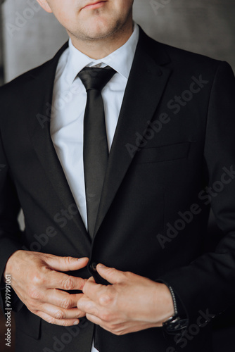 A man in a suit and tie is adjusting his tie