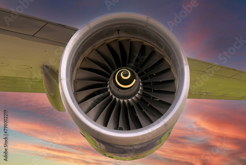 Close up view of a turbofan jet engine on an aircraft wing isolated against a colourful sunset sky. Travel concept.