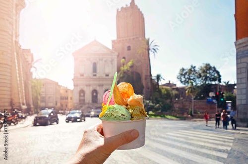 Italian bright sweet ice cream gelato cone with different flavors held in hand on the background of Piazza in Rome, Italy