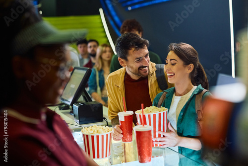 Young happy couple buying popcorn and drinks in cinema. photo